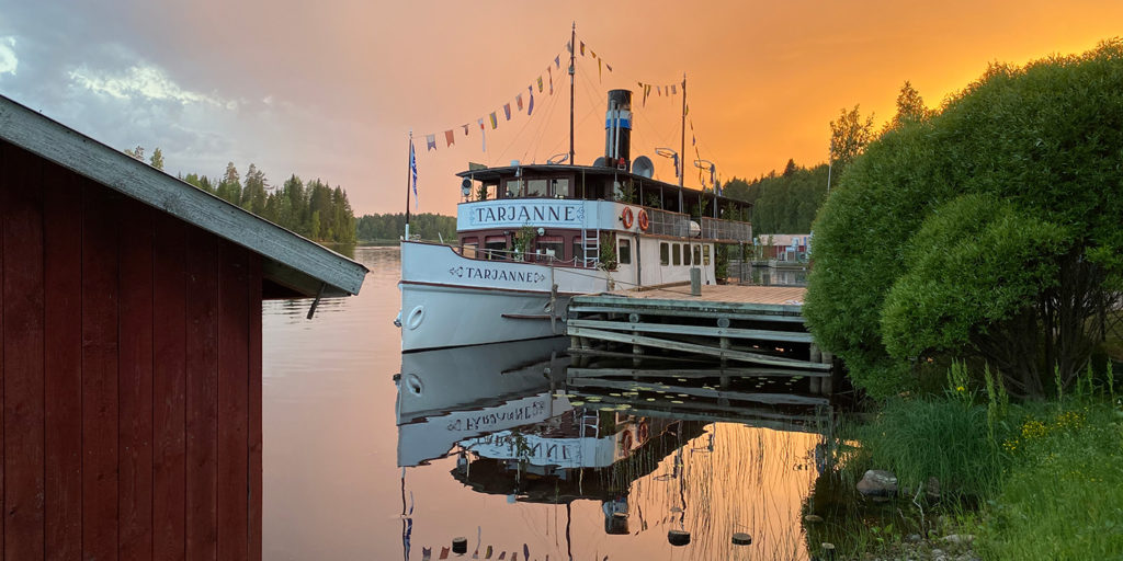 Tarjanne Virtain laivarannassa. Auringon lasku on värjännyt veden kultaiseksi.