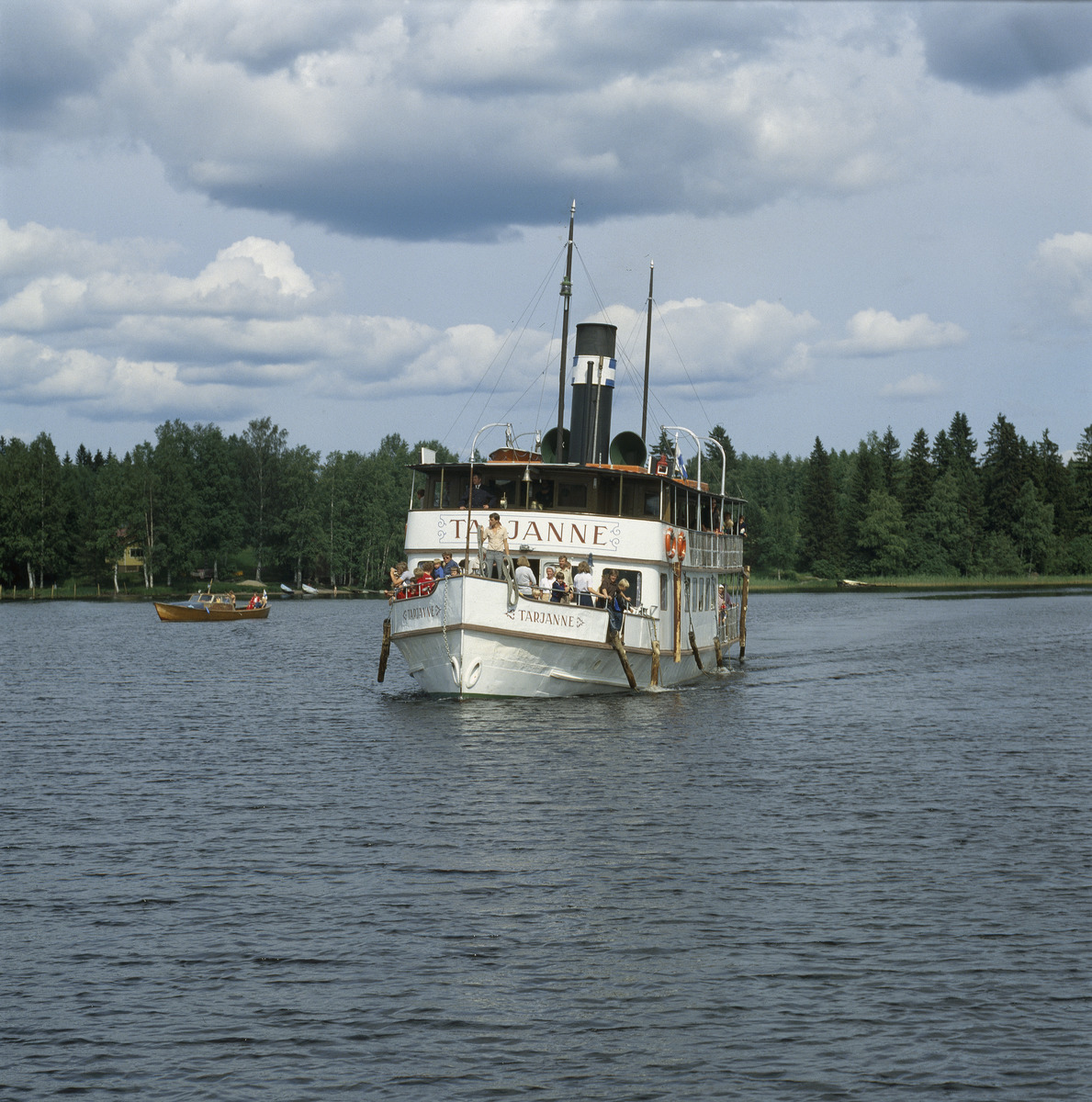 Tarjanne saapumassa Ruovedelle, kuva otettu laiturilta. Ihmisillä 1970-luvun vaatteet. Taustalla myös puinen moottorivene.